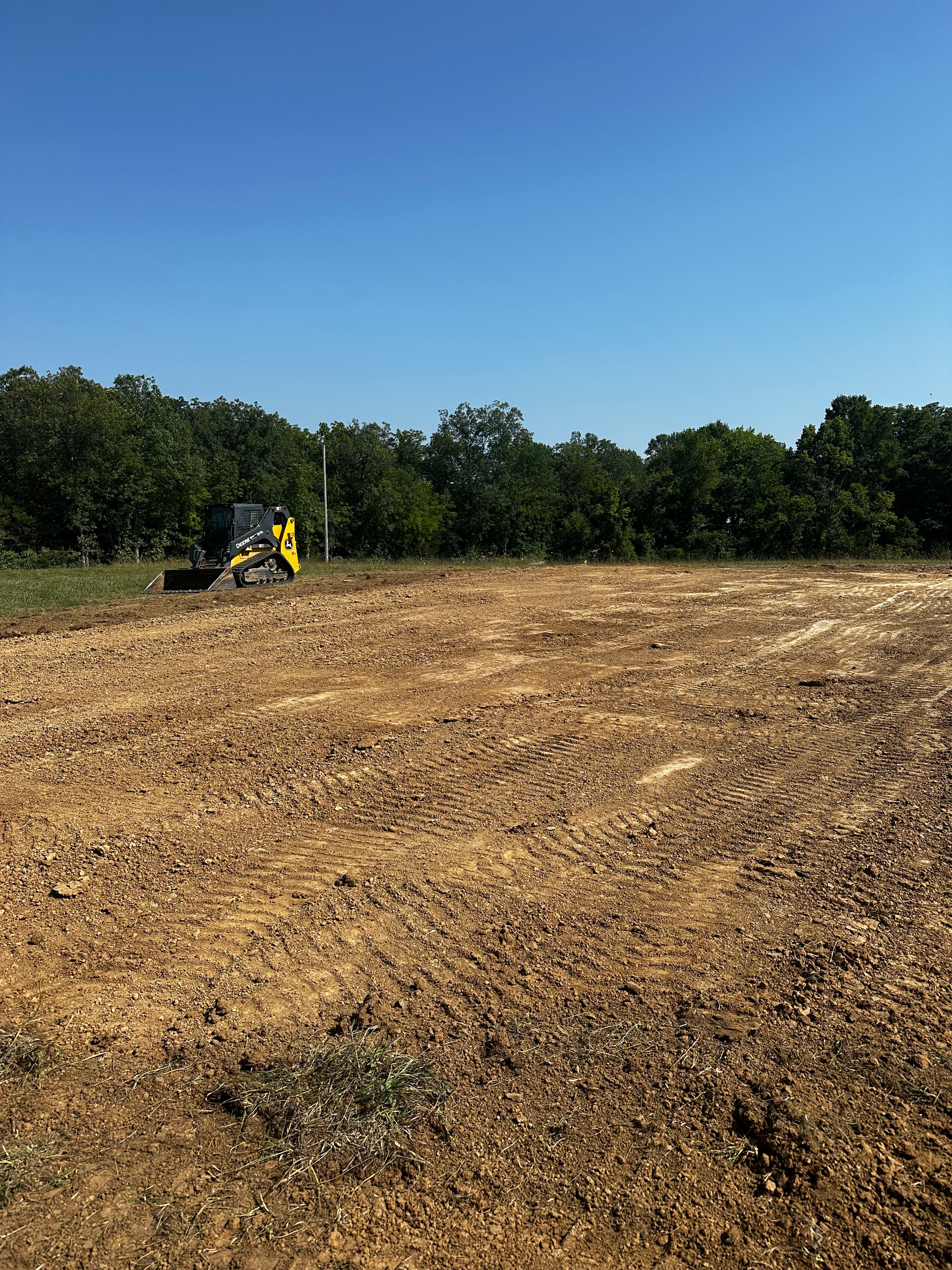 a yellow bulldozer is driving through a dirt field .
