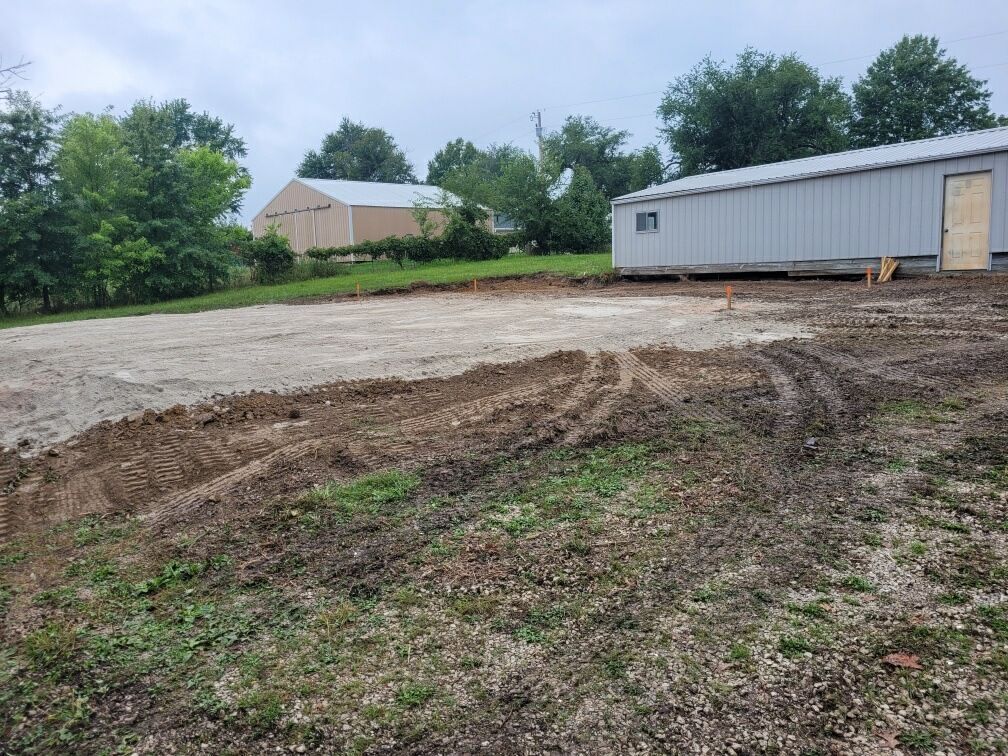 a large gray building is sitting in the middle of a dirt field .
