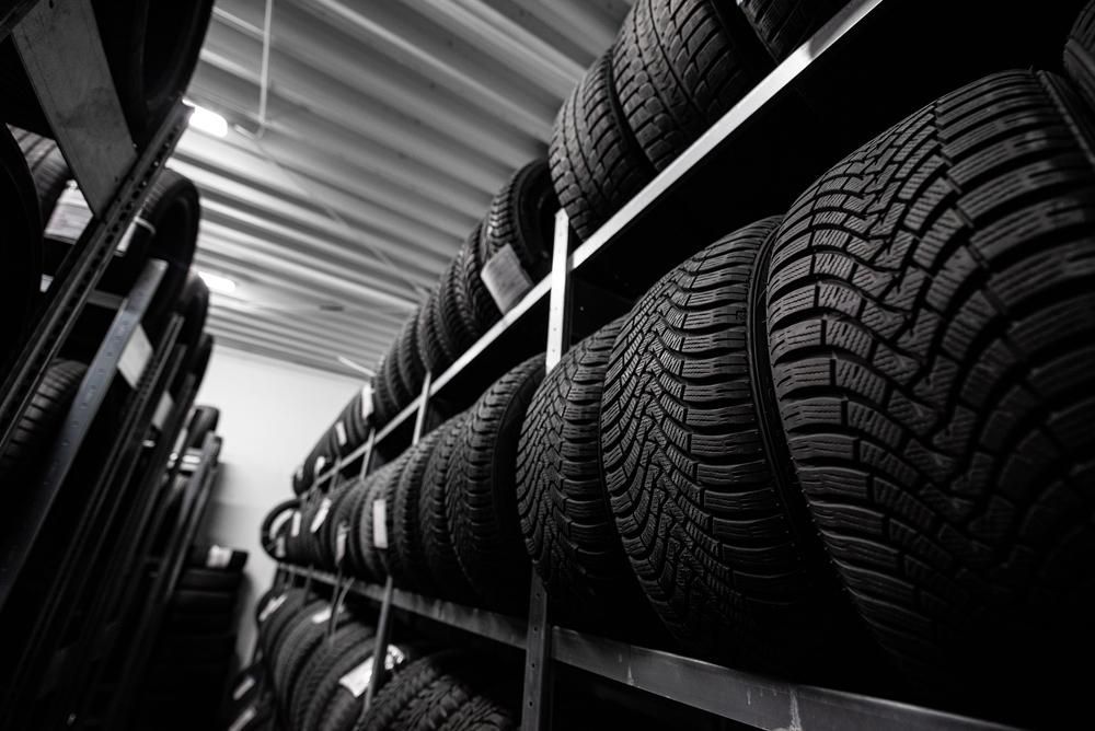 A Black and White Photo of A Warehouse Filled with Lots of Tires — Petersen's Second Hand & New Tyres in Currajong, QLD