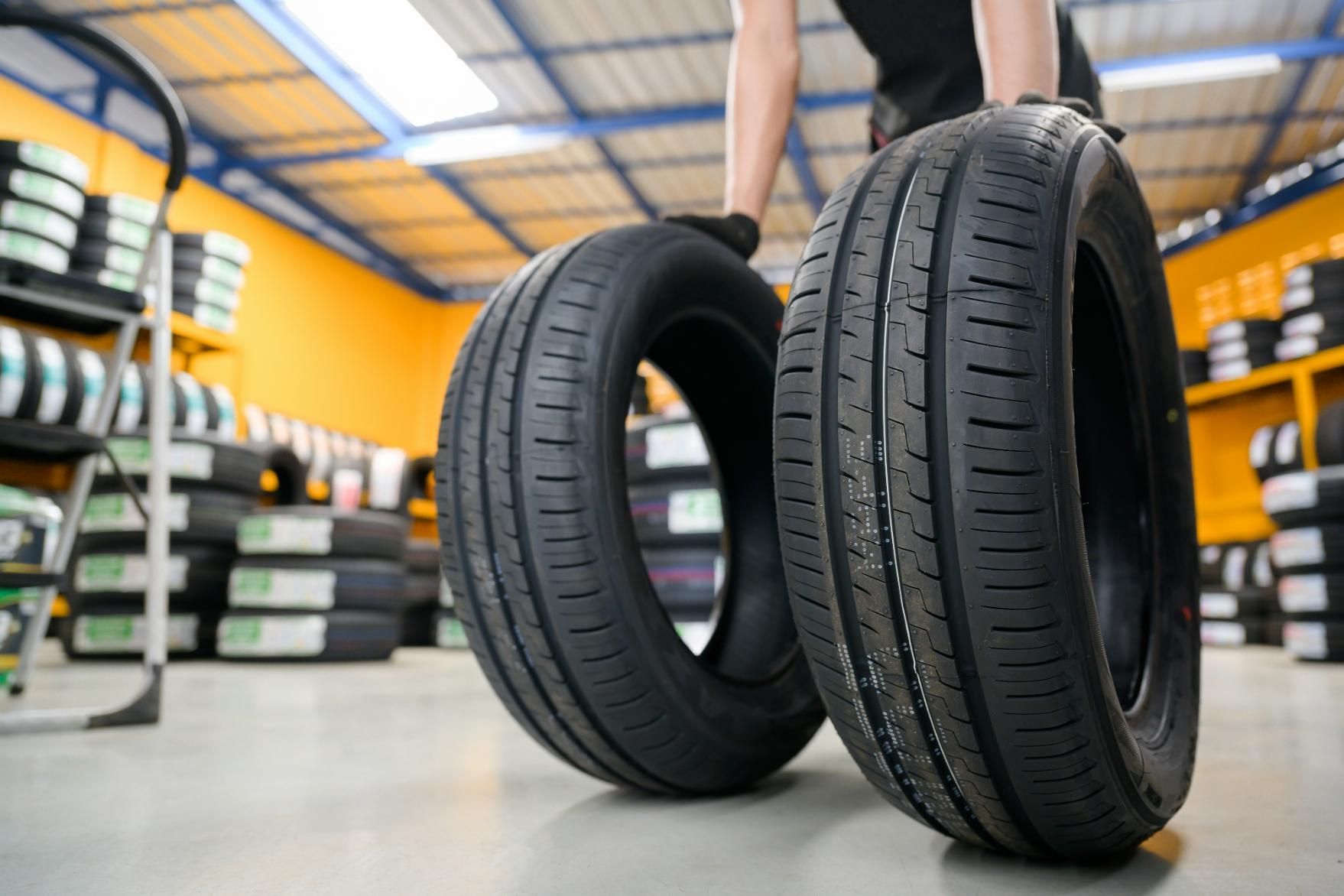 A Person Is Holding Two Tires in A Garage — Petersen's Second Hand & New Tyres in Currajong, QLD