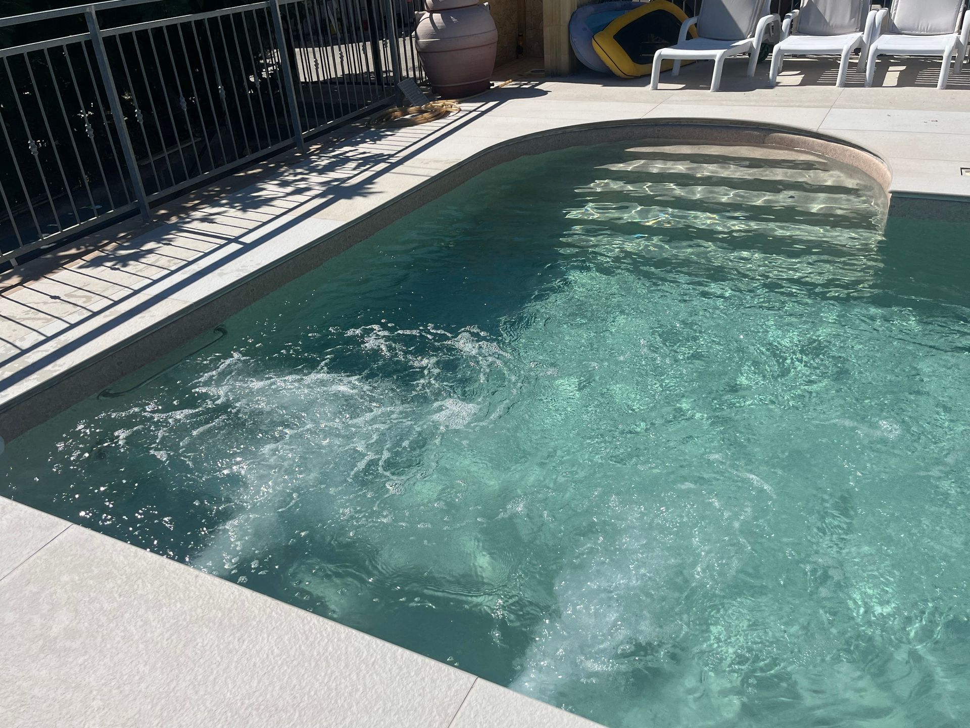 Piscina con spruzzi d'acqua, gradini e terrazza circostante.