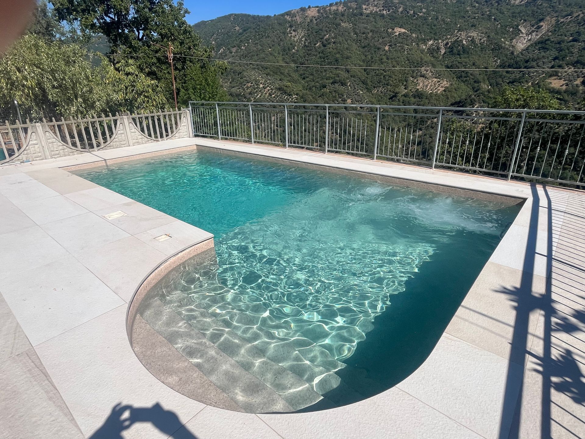Una piccola piscina rettangolare con acqua turchese e cristallina e un angolo curvo.
