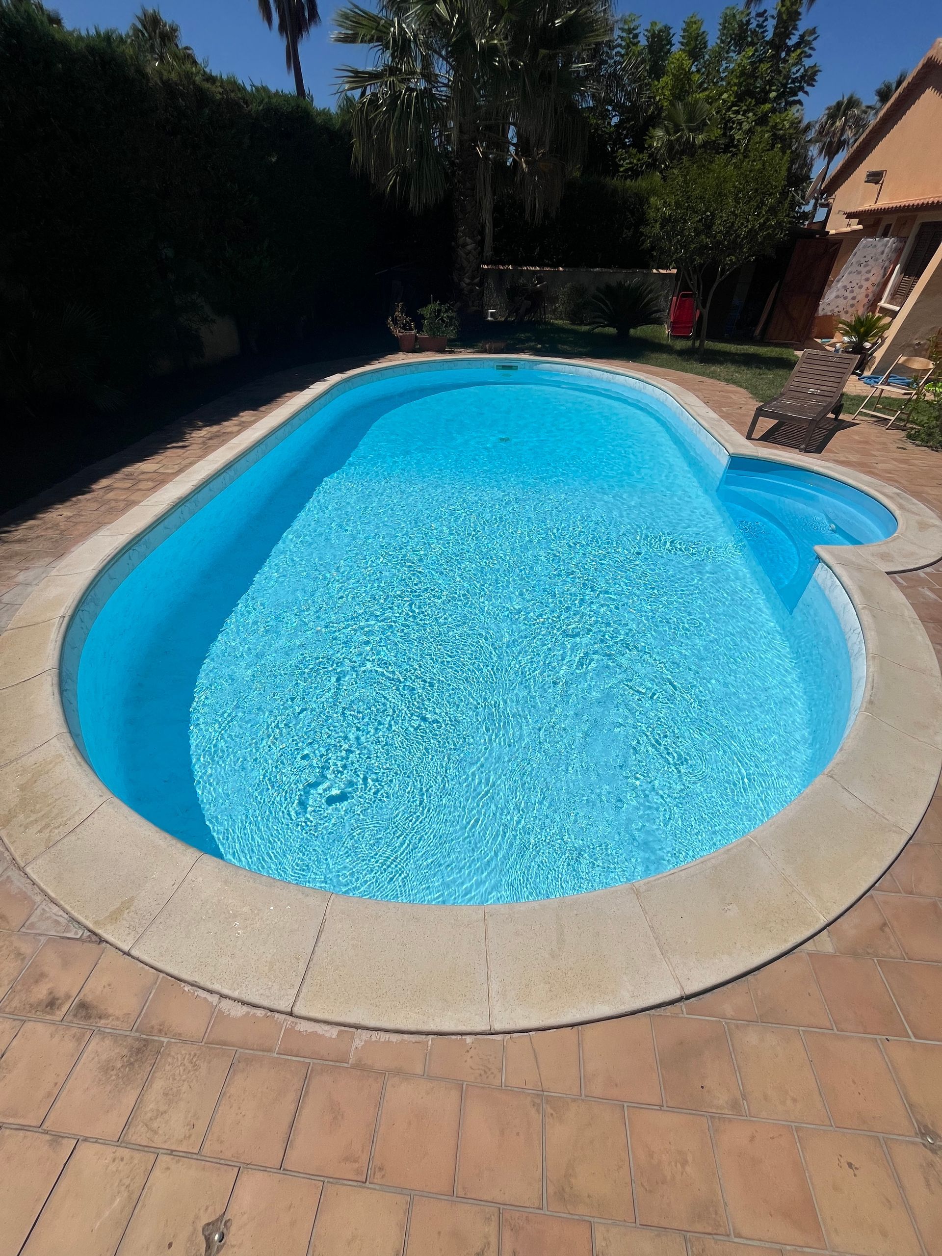 Piscina con acqua azzurra circondata da pietra e mattoni.