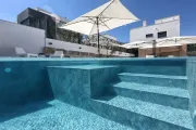 Piscina con gradini, acqua limpida, ombrellone bianco, moderni edifici bianchi, ambiente esterno soleggiato.