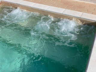 Acqua che gorgoglia in una piccola spa quadrata; piastrelle color cuoio lungo il bordo.