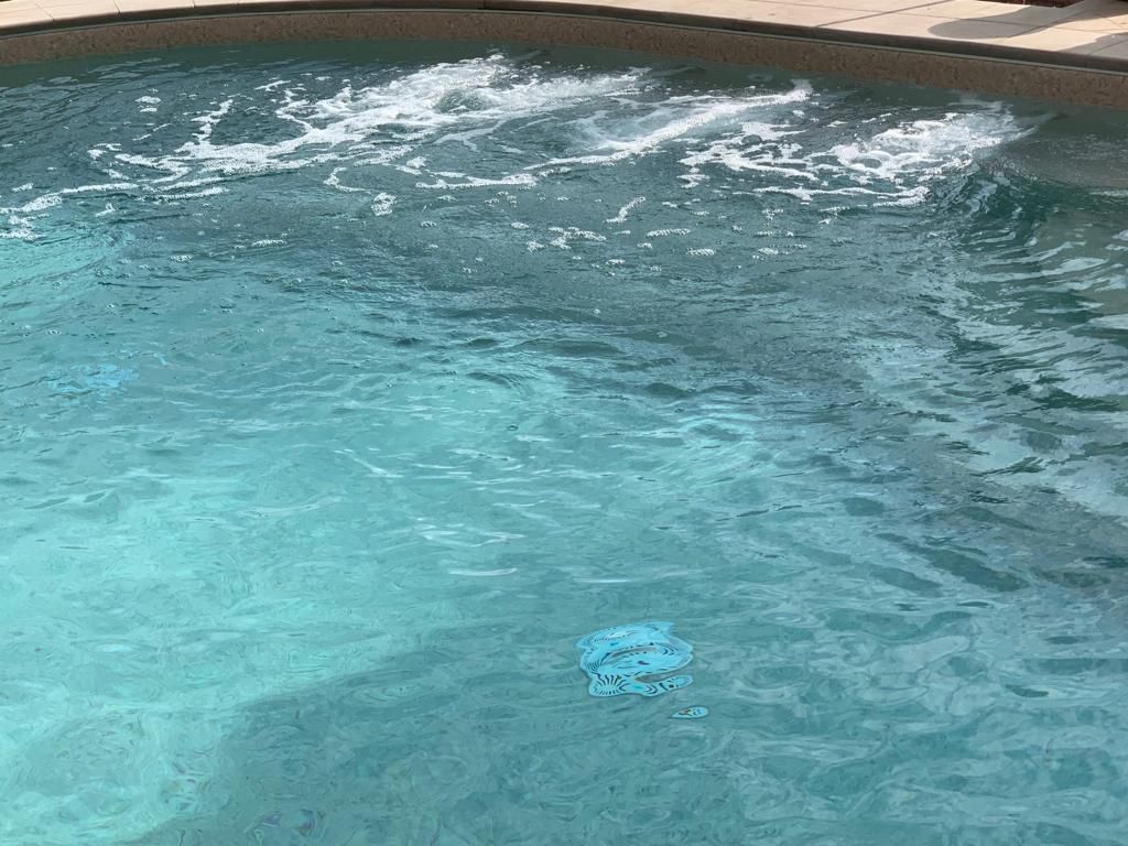 Una piscina con acqua turchese increspata, uno specchio d'acqua che crea spruzzi bianchi e schiumosi.