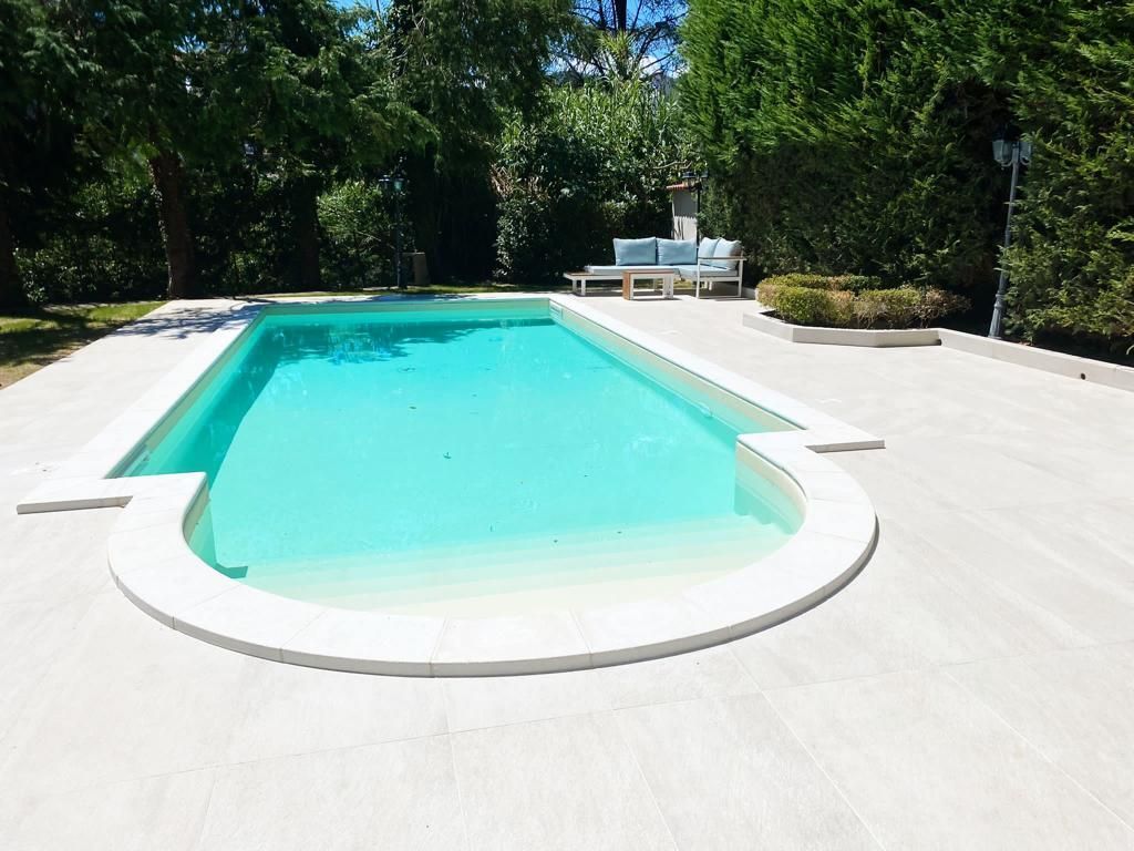 Piscina con acqua limpida circondata da un patio bianco