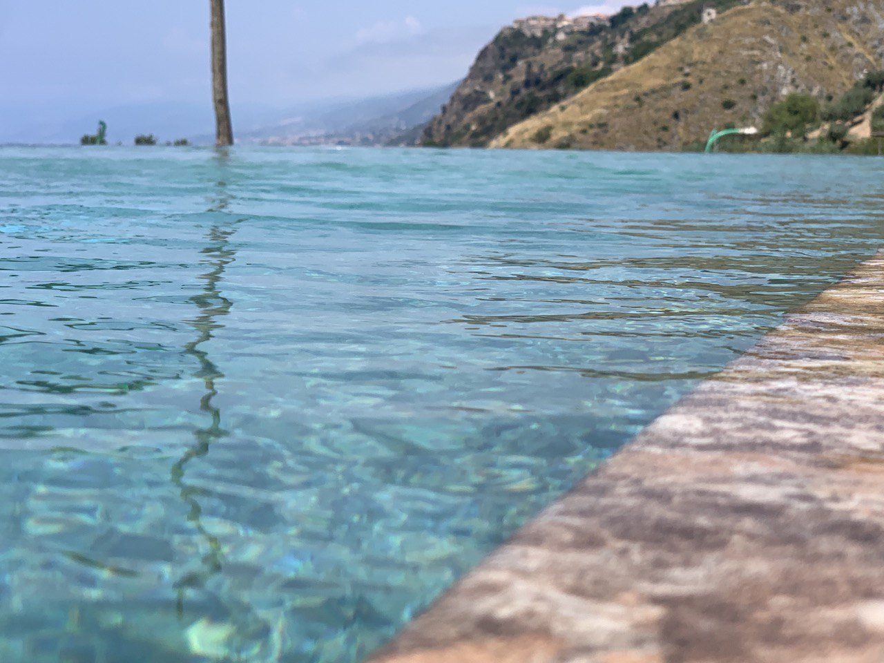 Una piscina limpida con le montagne sullo sfondo; l'acqua è turchese e increspata.