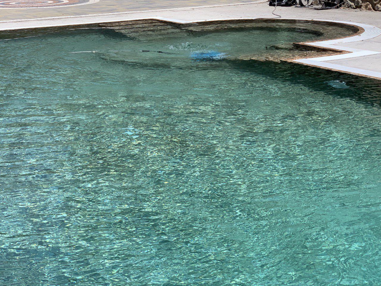 Acqua turchese e limpida in una piscina con riva sabbiosa, che si increspa nelle giornate di sole.