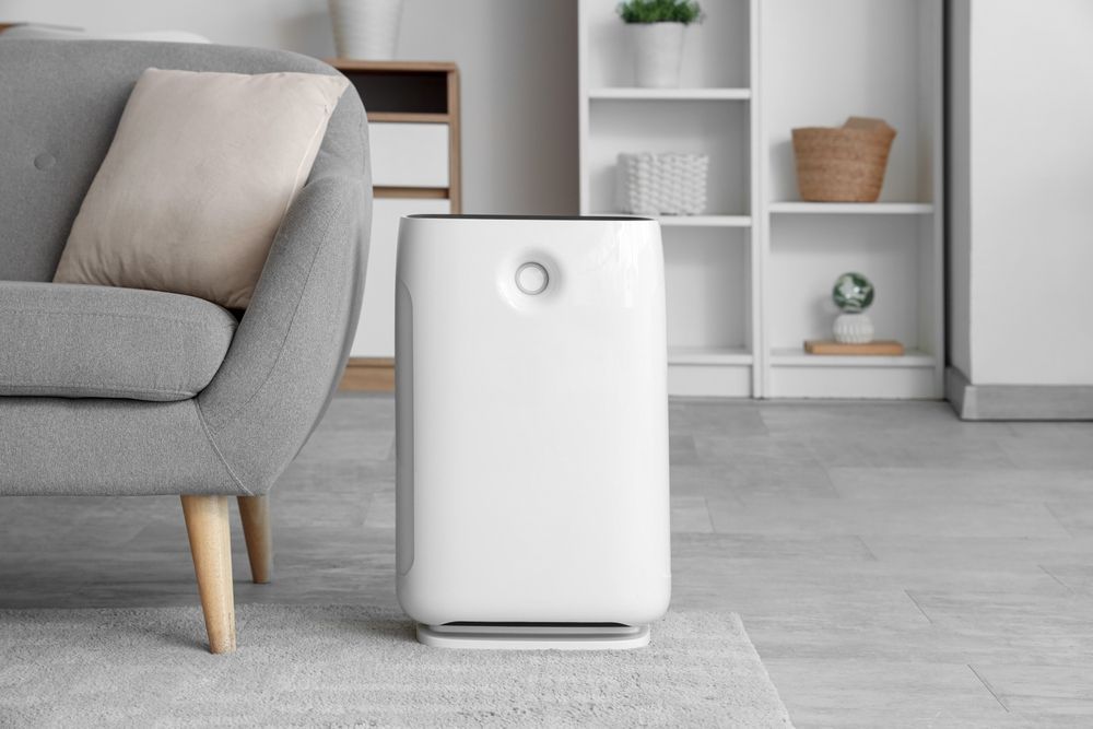 White air purifier beside a gray sofa in a modern living room