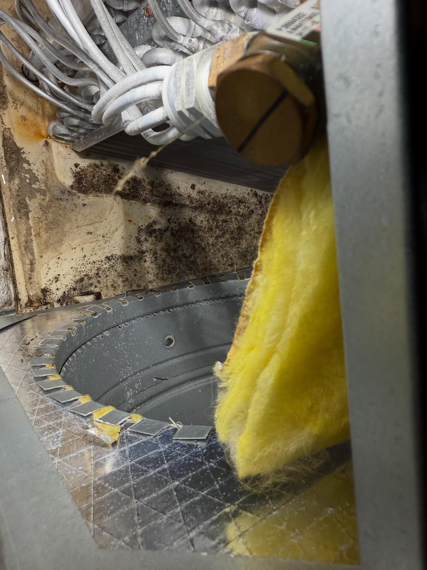 Yellow insulation inside a dusty industrial duct with cables and a metal floor grate