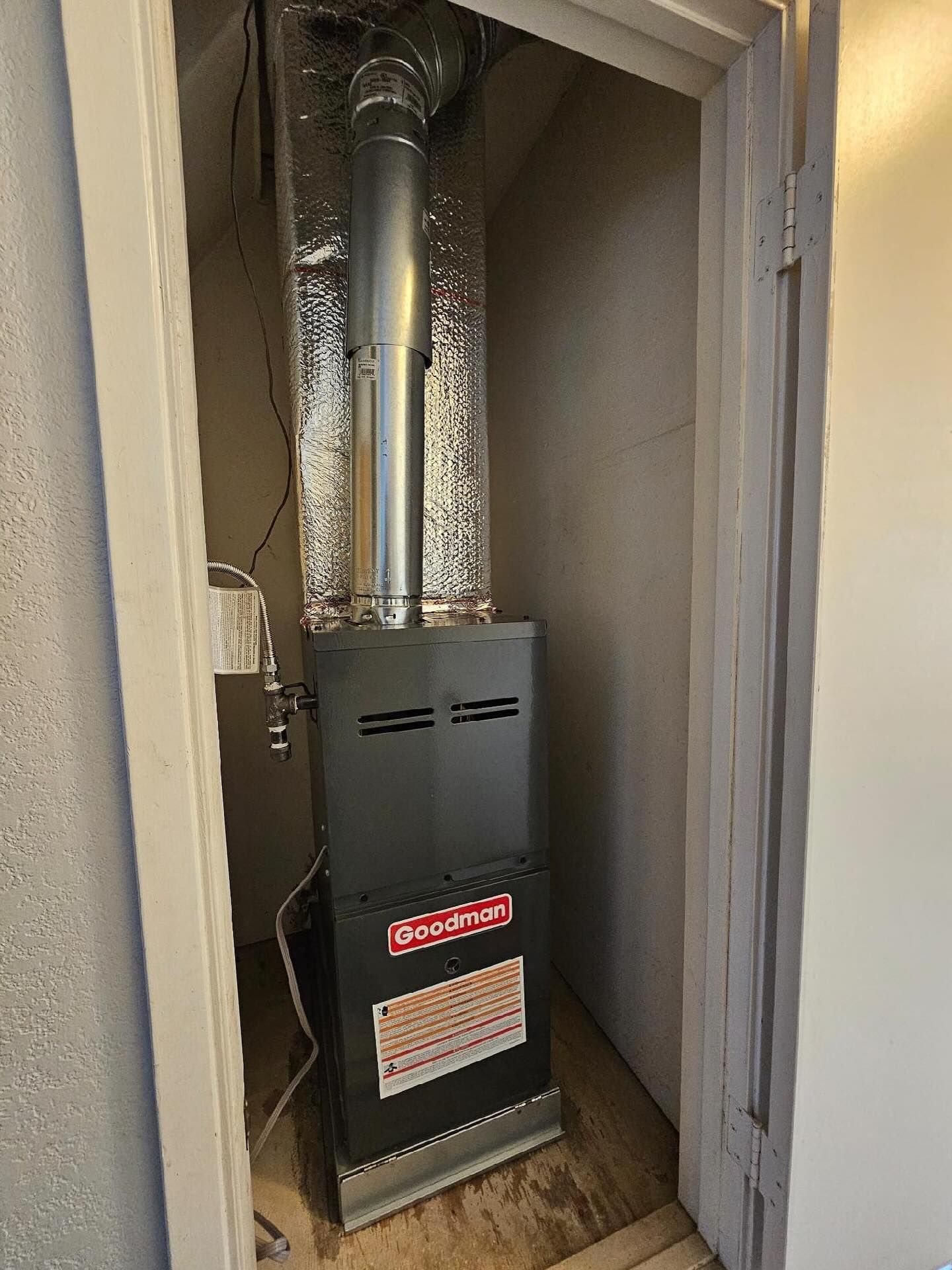 Furnace with metal ductwork in a narrow utility closet.