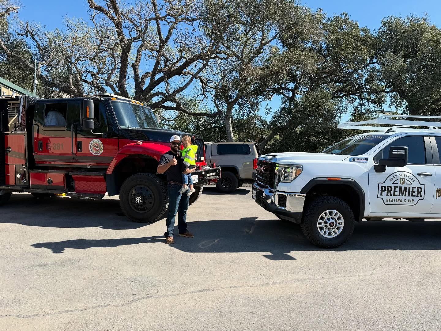 Fire trucks and a white rescue pickup parked on a street, with a firefighter standing between them.