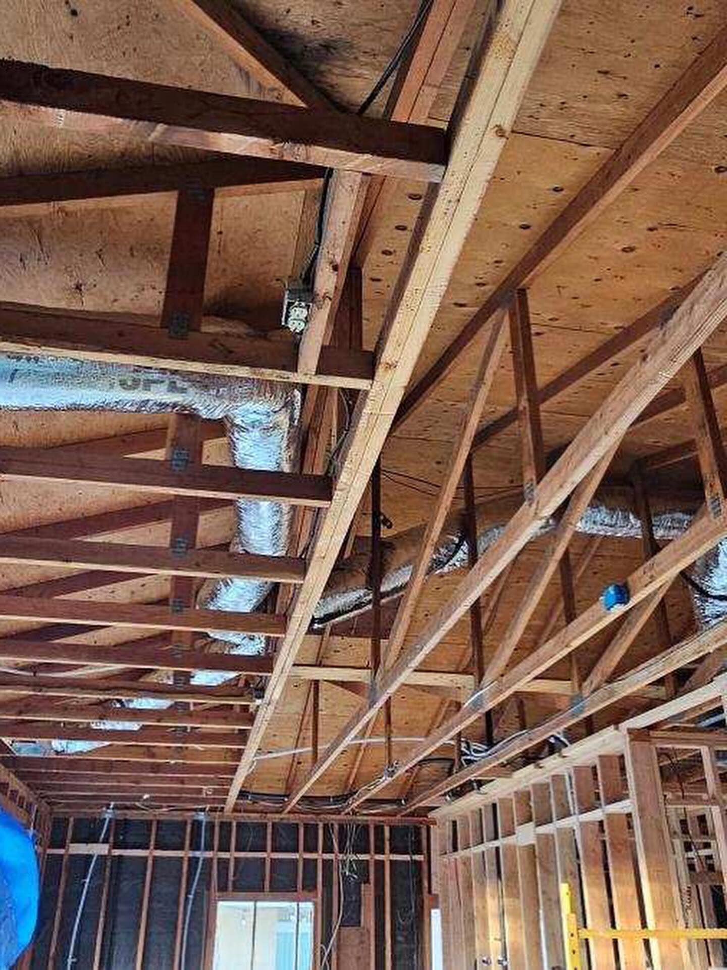 Wood-framed attic under construction with exposed rafters and plywood roof sheathing