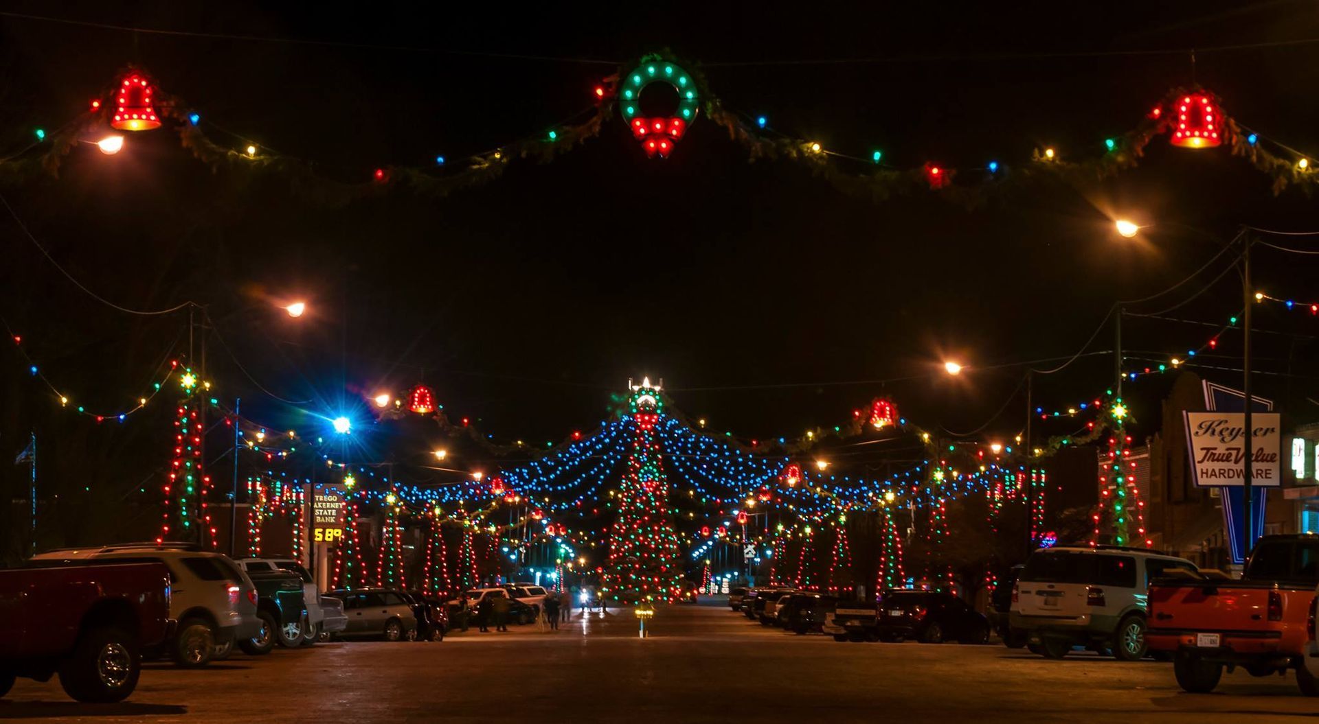 Street lined with Christmas lights and decorations at night.