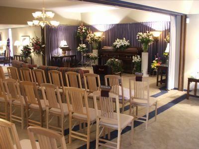 Rows of wooden chairs facing a decorated stage in a banquet hall