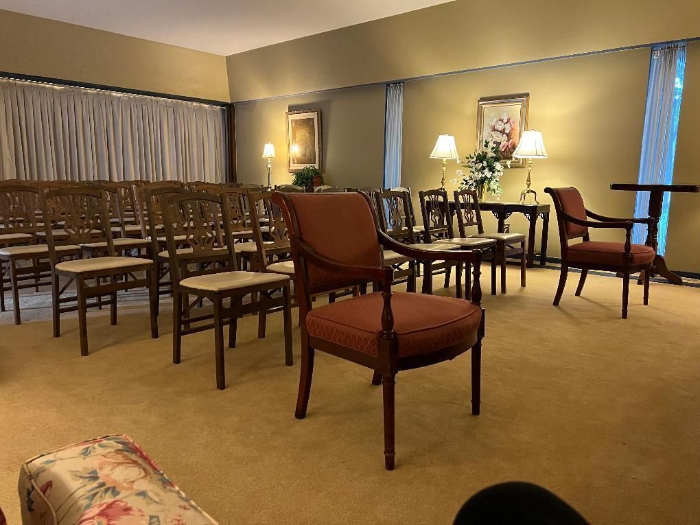 Empty banquet room with rows of chairs, small tables, and warm lamp lighting on beige carpet.