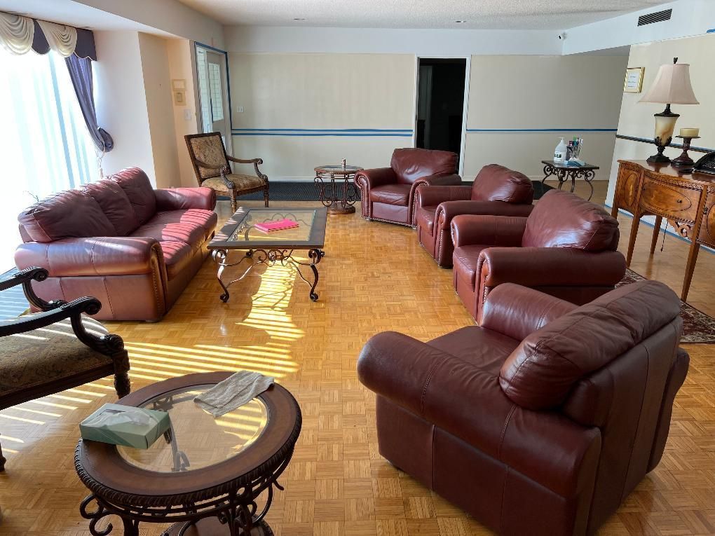 Living room with burgundy leather sofas, coffee tables, and sunlight on wood floors