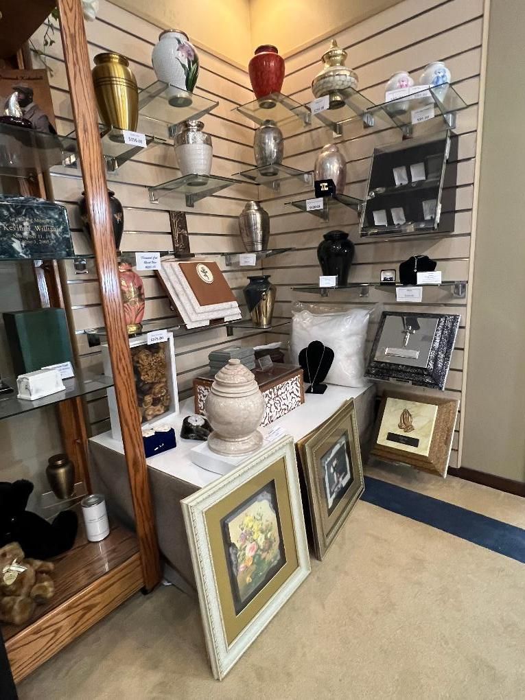 Decorative store display with framed art, vases, glassware, and small home décor items on shelves and floor