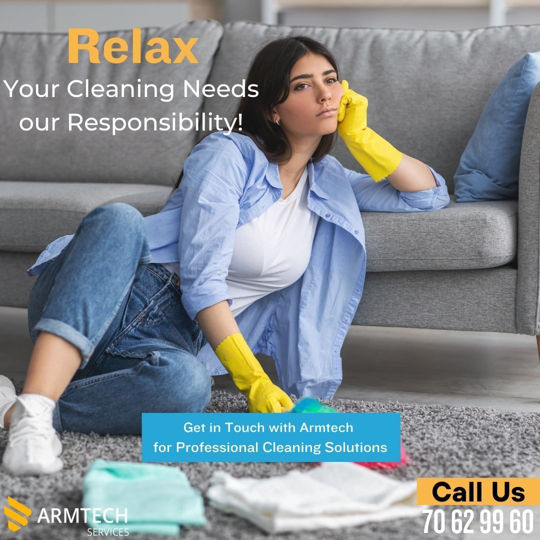 A woman wearing yellow gloves is cleaning the floor in front of a couch