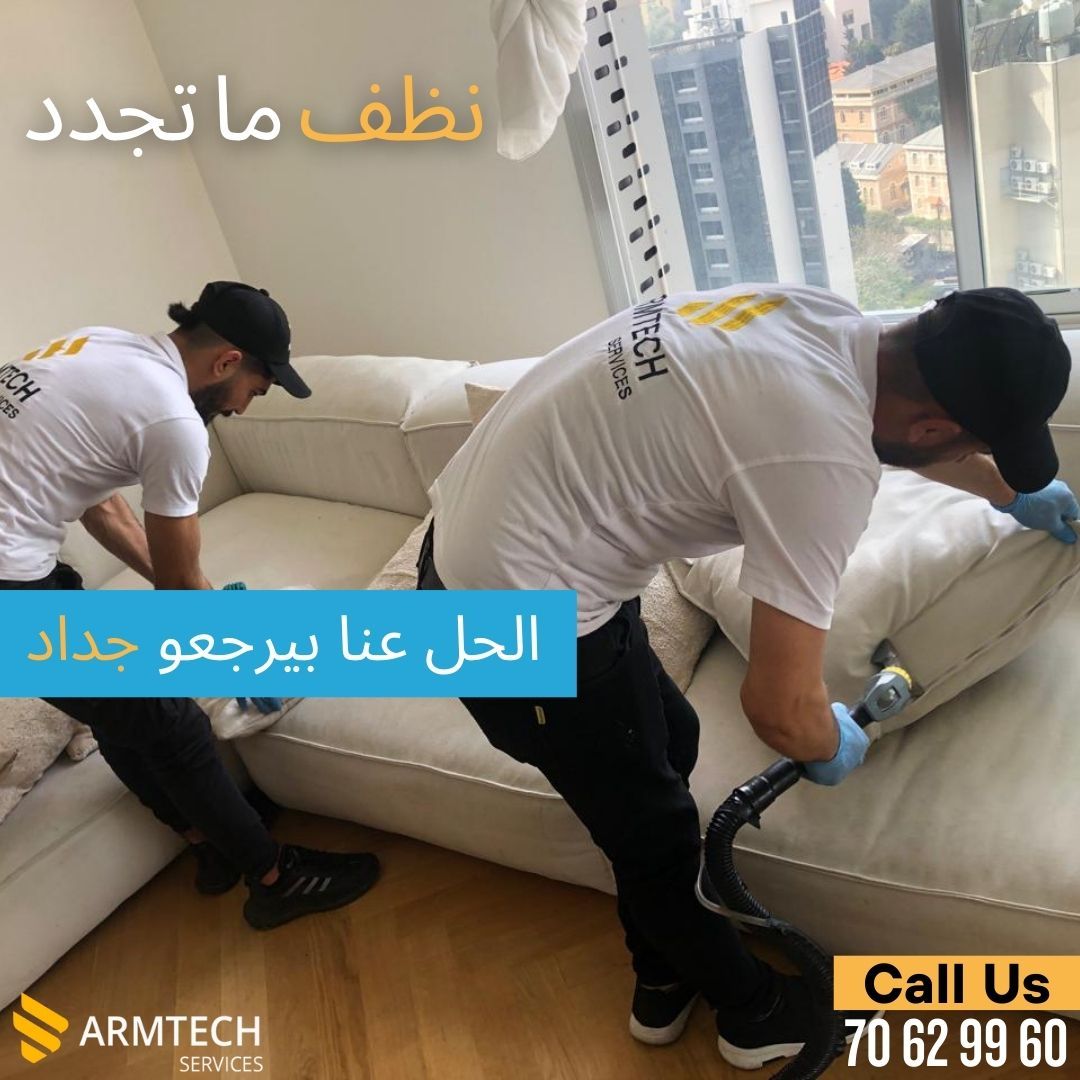 Two men are cleaning a white couch with a vacuum cleaner