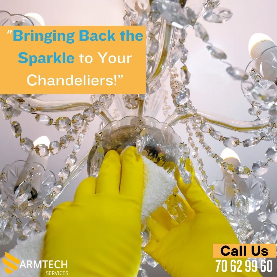 A person wearing yellow gloves is cleaning a chandelier