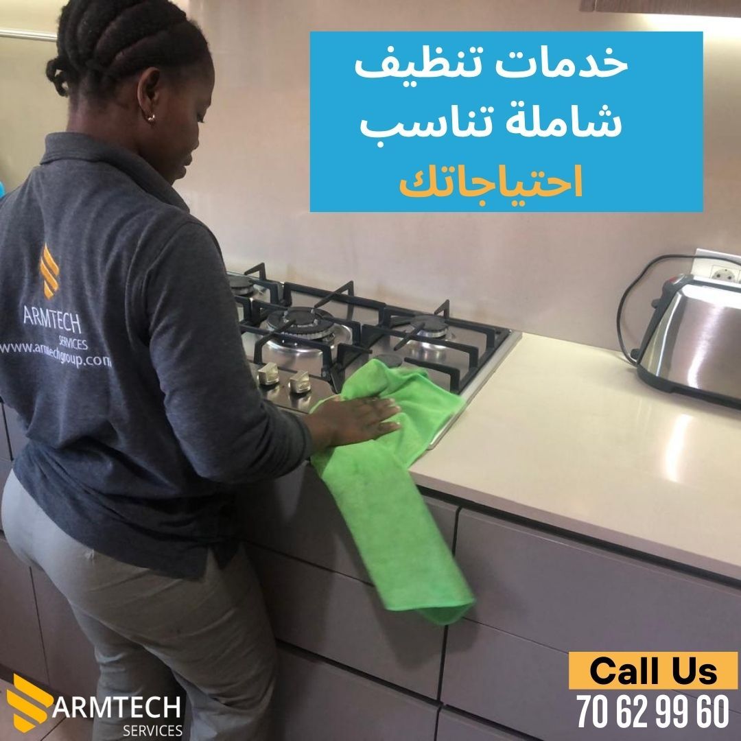 A woman is cleaning a stove top with a green cloth