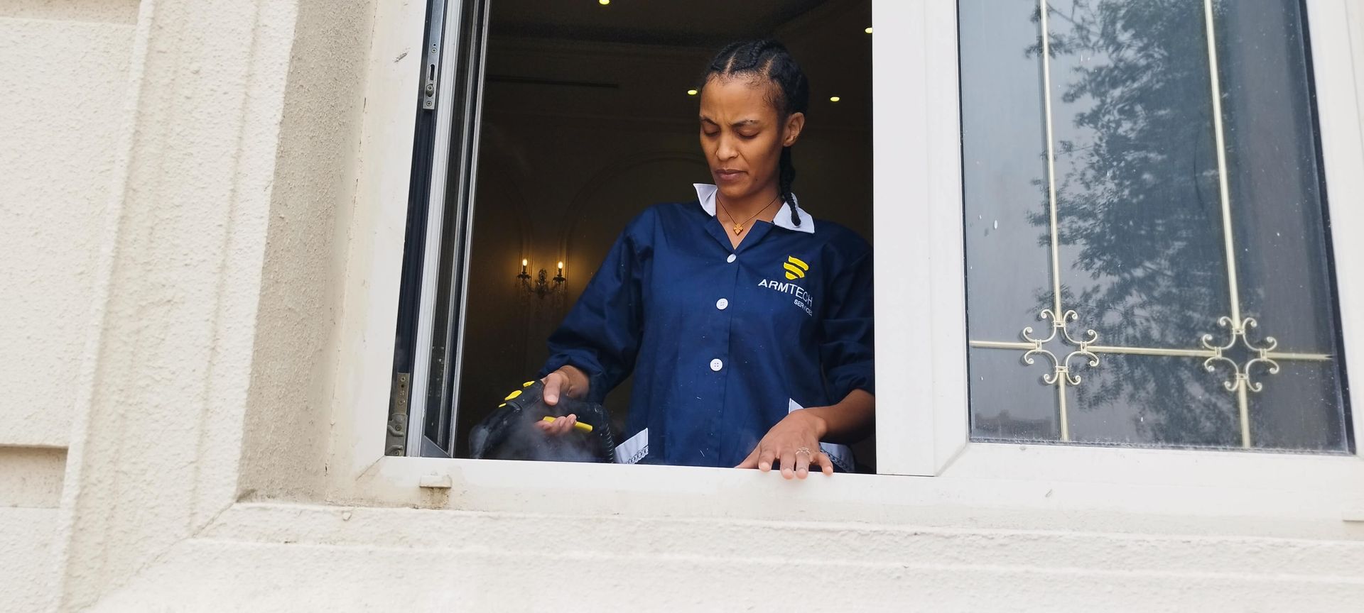 A woman in a blue shirt is cleaning a window