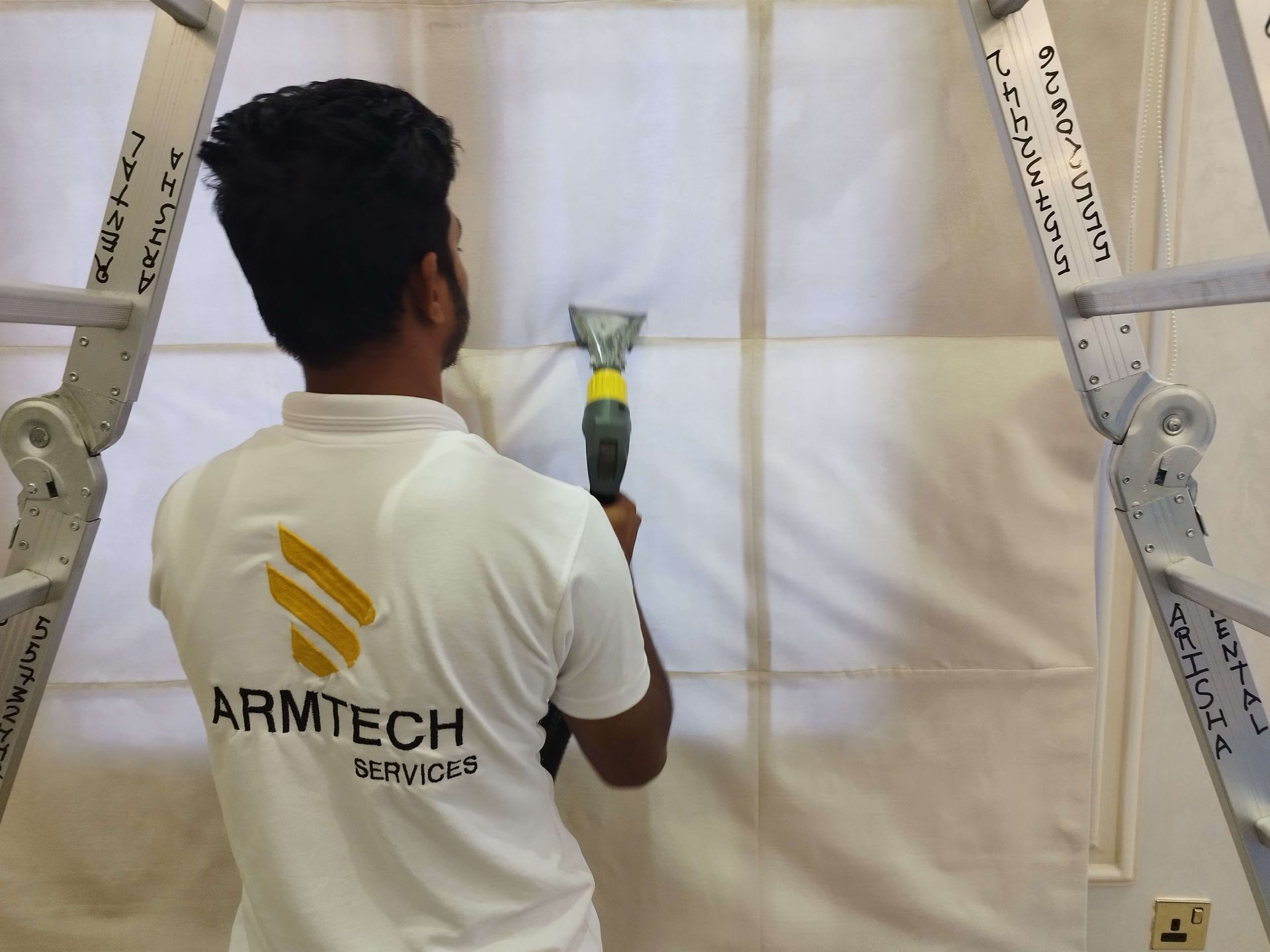 A man wearing a white shirt that says armtech on the back
