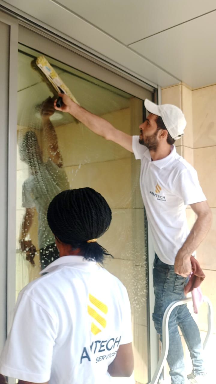 A man and a woman are cleaning a glass door
