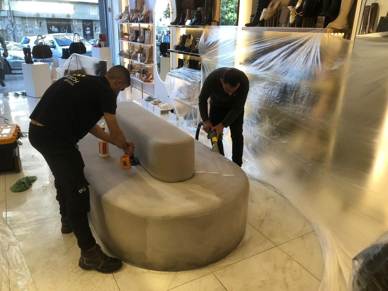 Two men are working on a round couch in a store