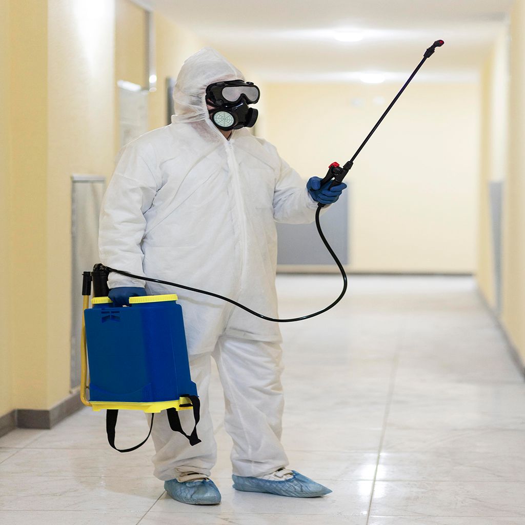 Two people in protective suits are cleaning an office.