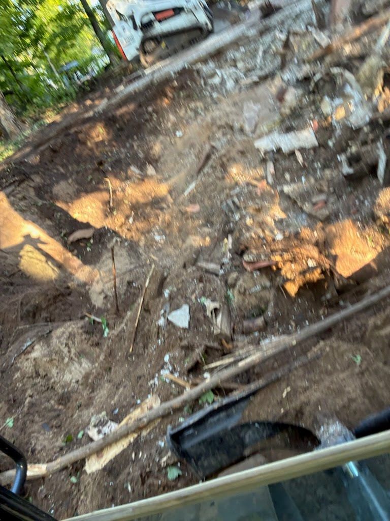 Tilted view of a muddy hillside with scattered debris, broken wood, and a parked car near the top.