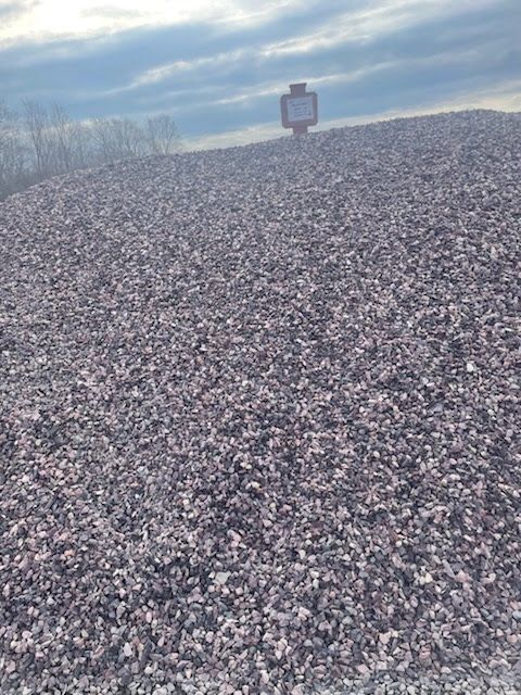 Gravel mound under a cloudy sky with a small sign at the top