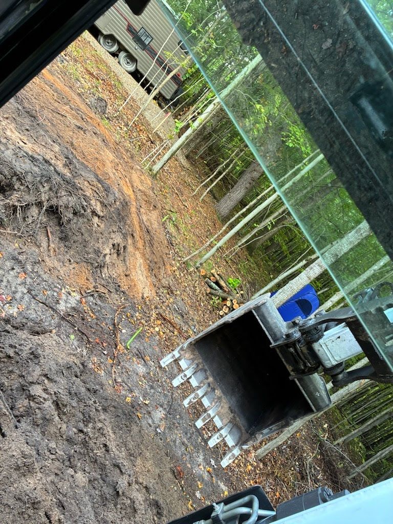 Backyard construction site with muddy ground, trench, and a small excavator near a fence