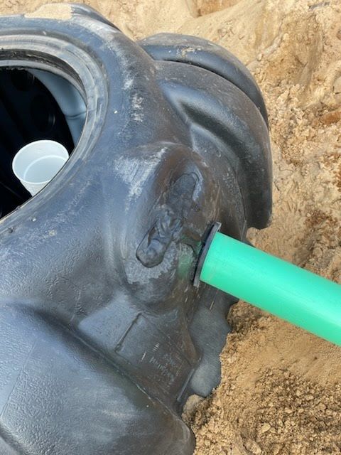 Black tire in dirt with bright green pipe inserted into its side