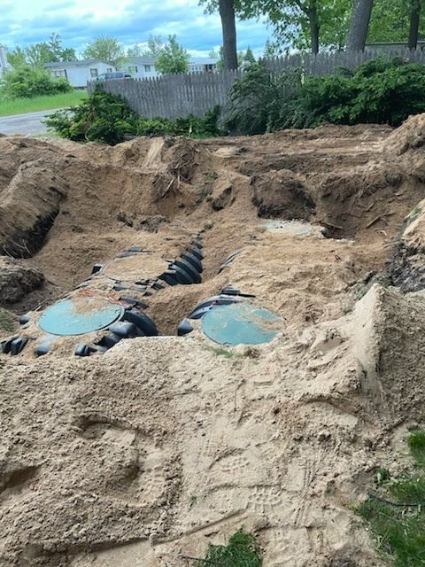 Sand pit excavation with two blue circular covers and black corrugated pipe under construction