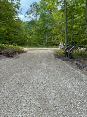 Gravel road through a green forest with parked bicycles on the right side