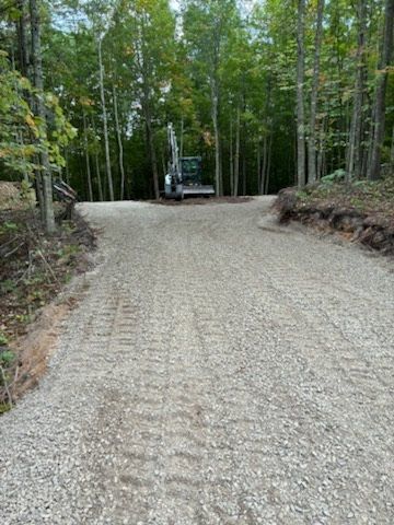 Gravel road curving through a wooded area with a parked vehicle ahead