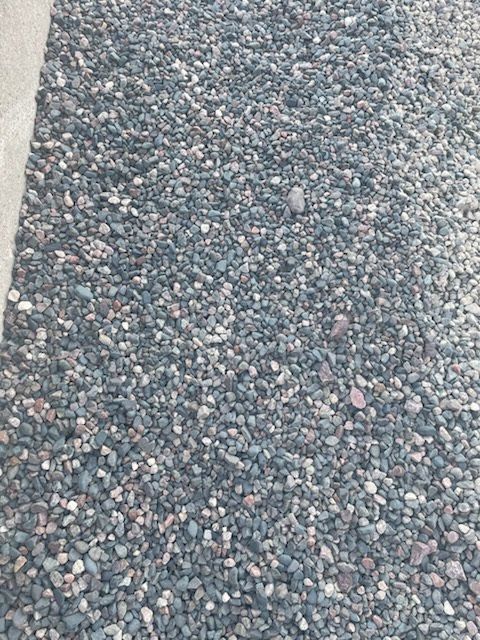 Close-up of gray and pink gravel with a pale concrete edge on the left