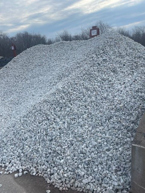 Large pile of white gravel or crushed stone outdoors under a cloudy sky