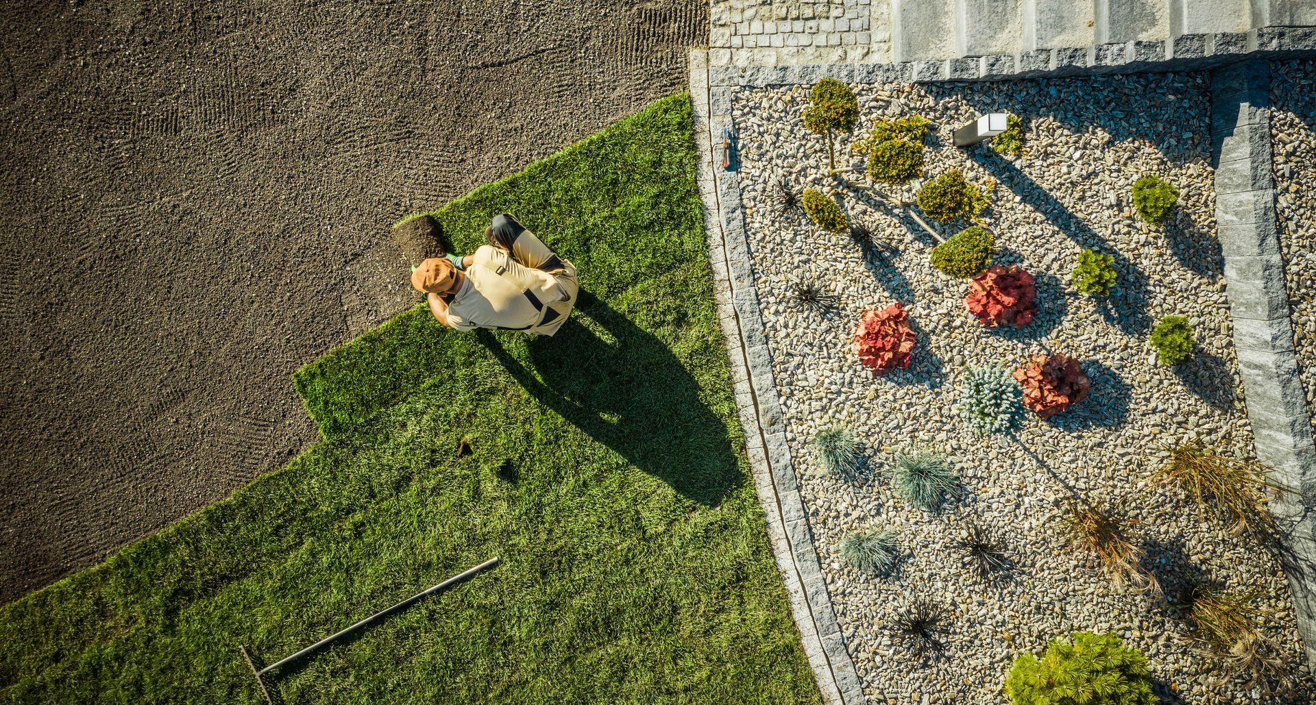 An aerial view of a man cutting a lawn with a lawn mower.