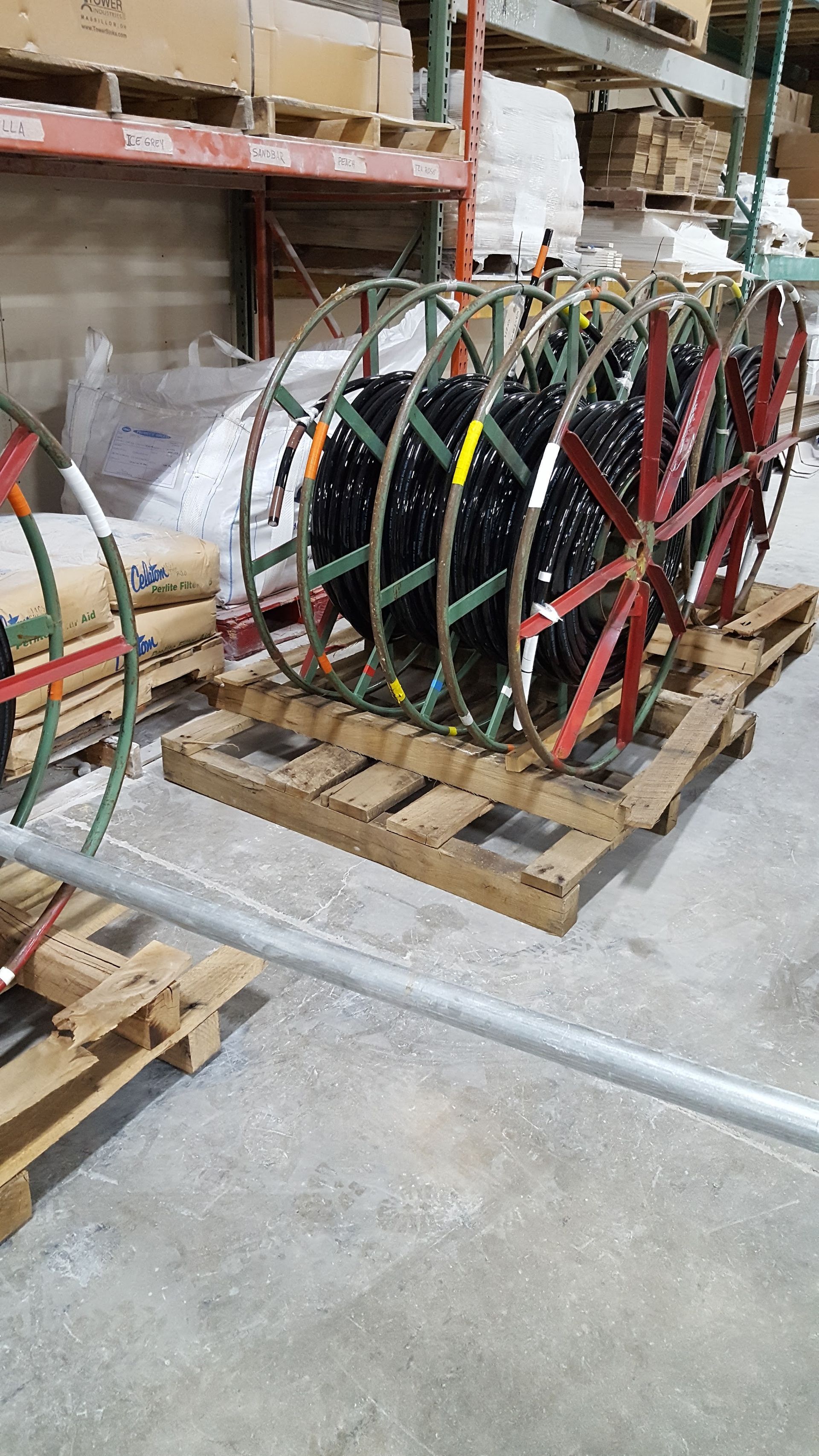 Colorful coiled hoses or cables on wooden pallets in a warehouse aisle