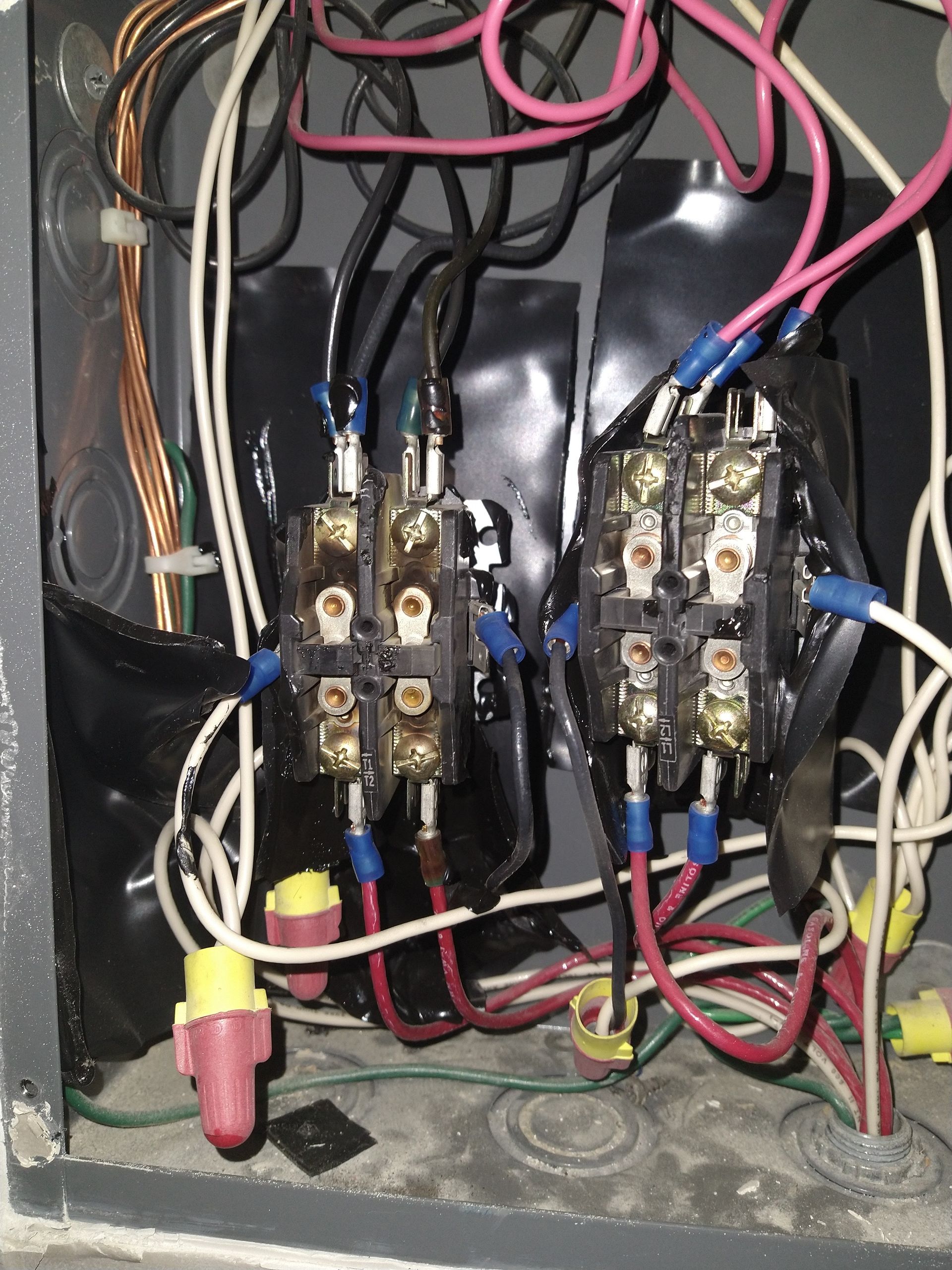 Electrical panel with exposed wiring and two relay/contactor units inside a metal box