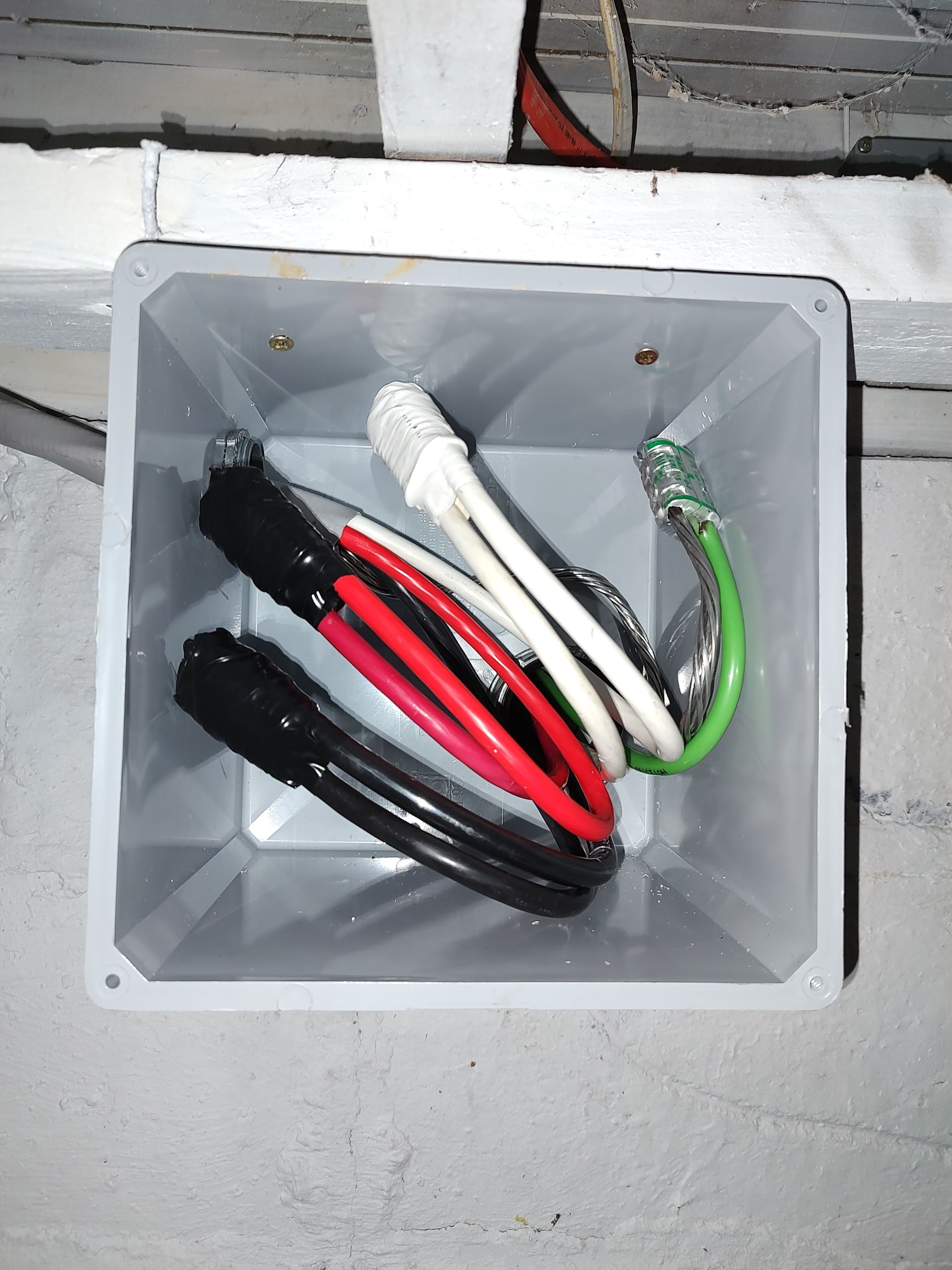 Plastic electrical junction box with red, black, white, and green wires inside