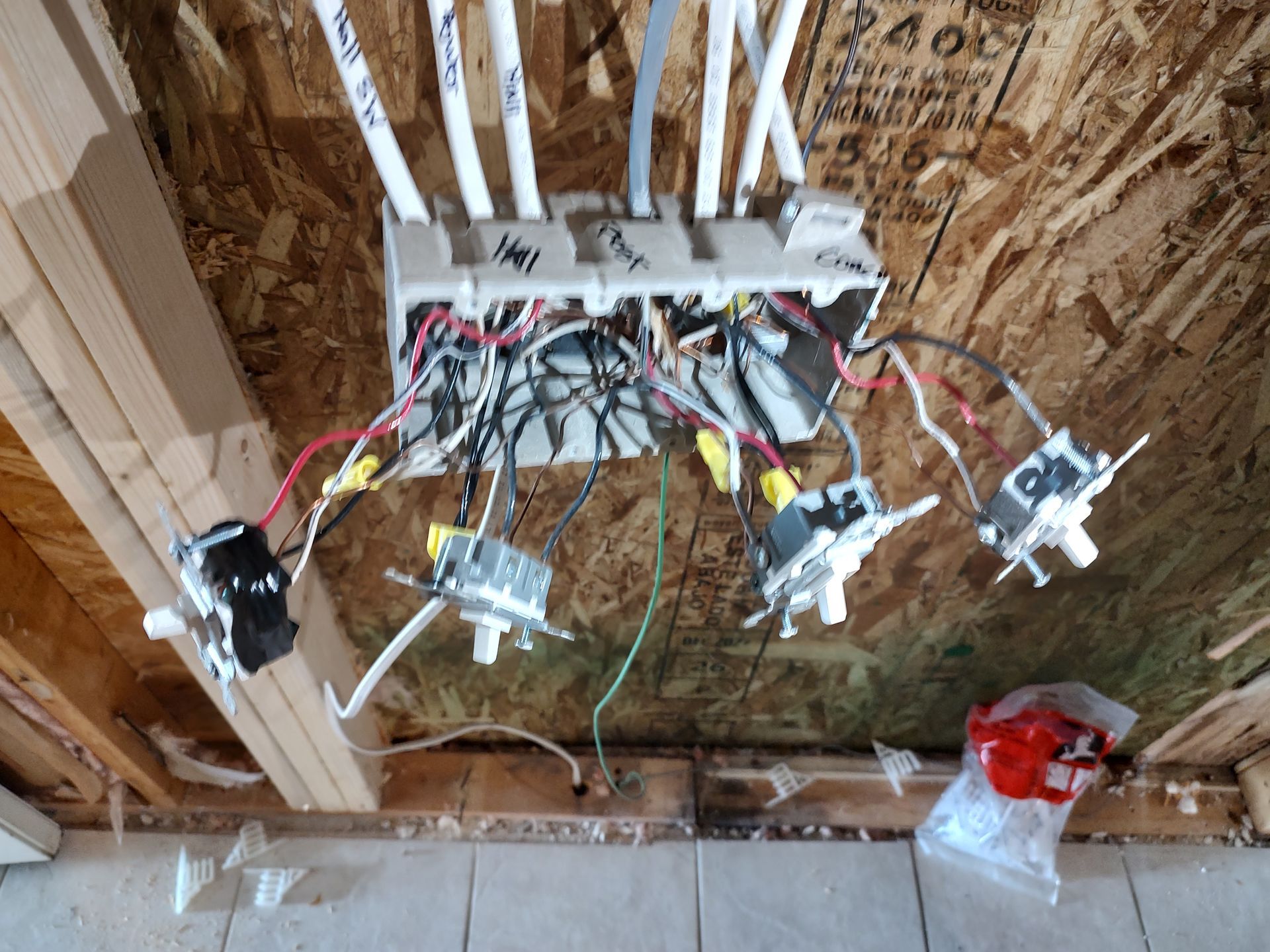 Exposed electrical wiring and outlets mounted on unfinished plywood wall framing.