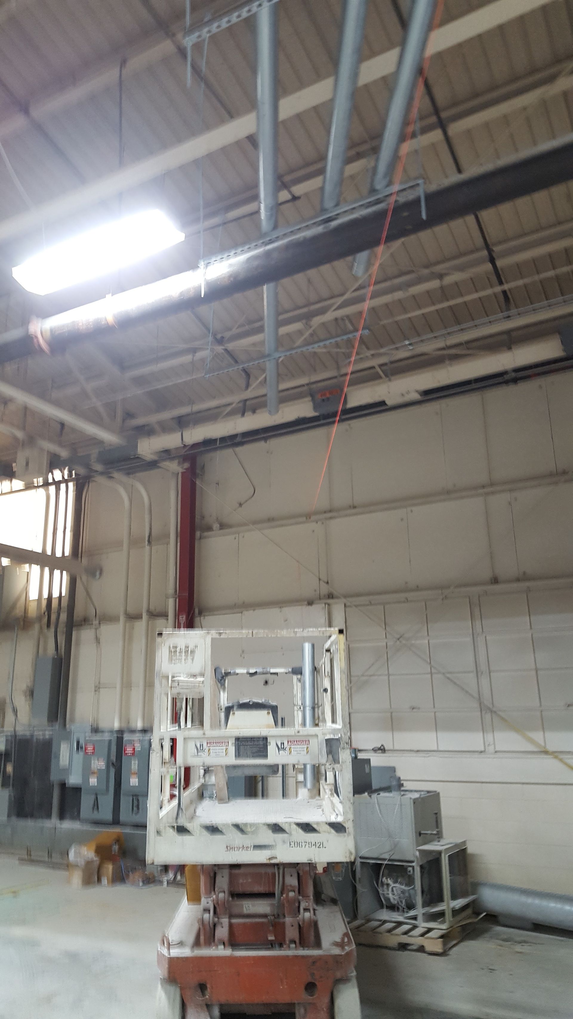 Industrial factory interior with a suspended machine or platform under bright overhead lights