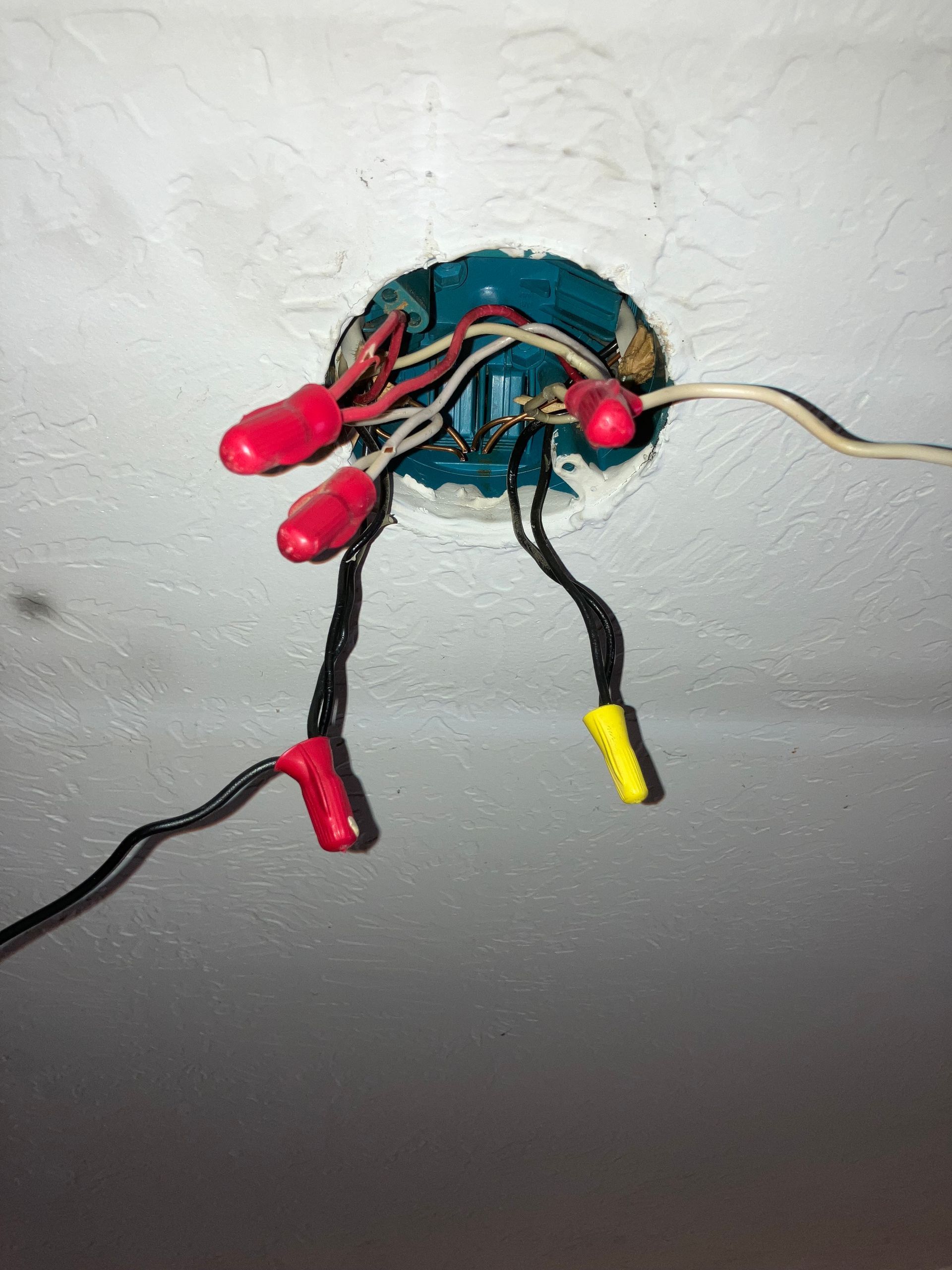 Small homemade circuit with red and yellow wires mounted on a white wall surface