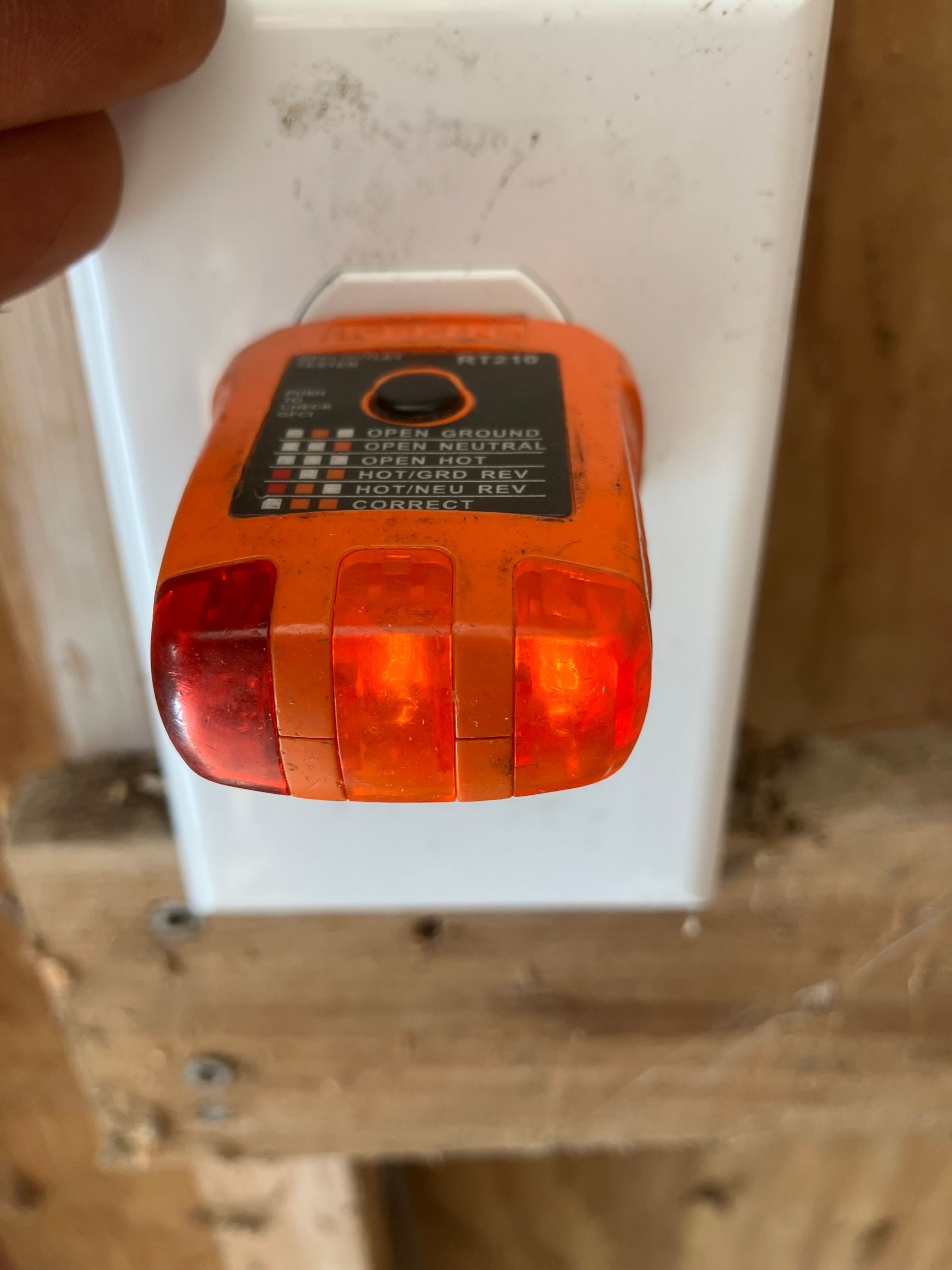 Orange outlet plug-in night light on a white wall plate above a wooden shelf.
