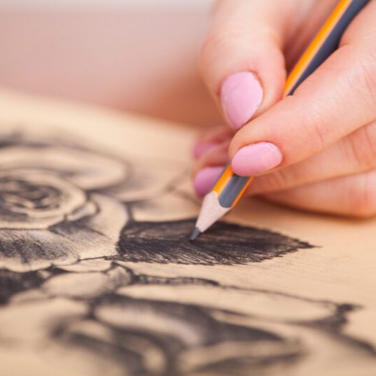 Hand shading a charcoal drawing with a pencil on paper